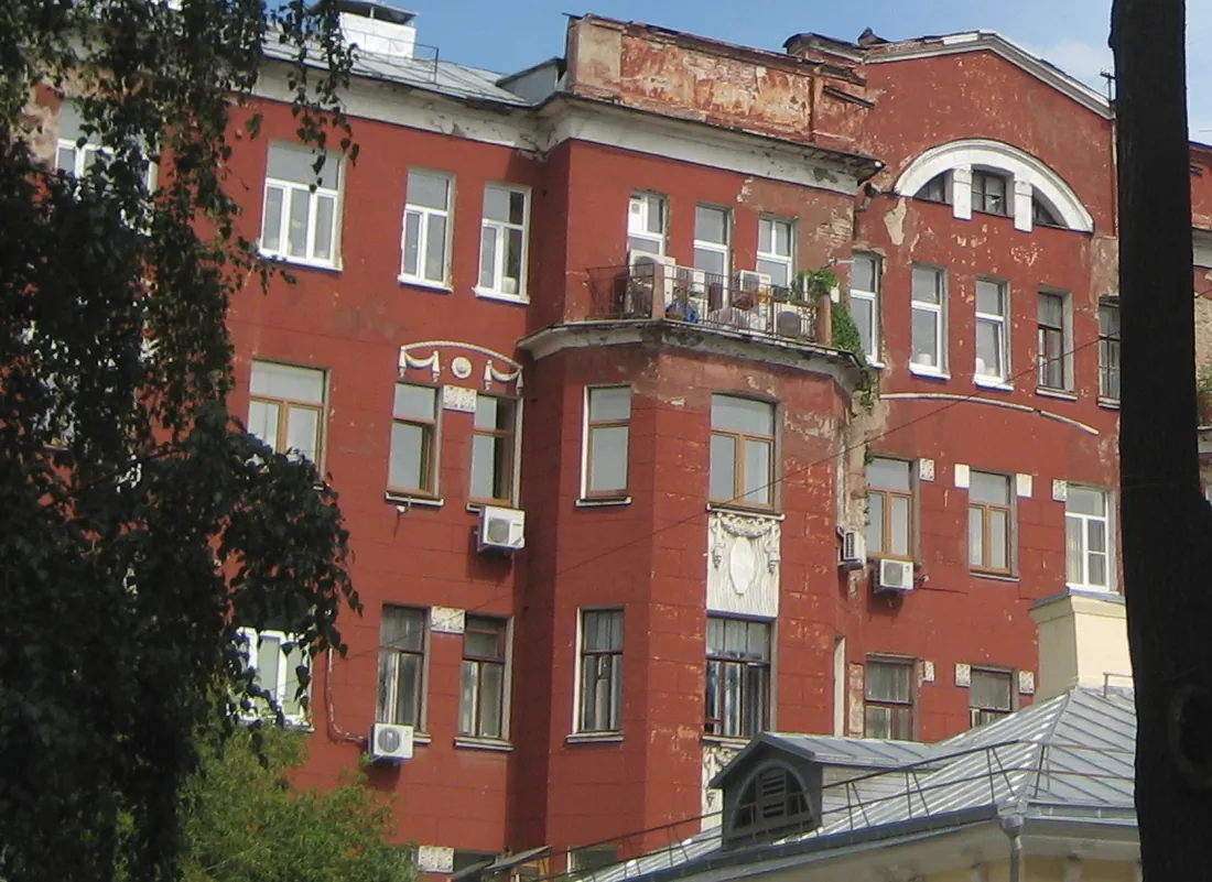 Фрагмент фасада дома в Малом Лёвшинском переулке, 7 в 2012 году: эркер с балконом, лепная гирлянда с розеткой, четыре блока кондиционеров и кабель, протянутый по кирпичной кладке
